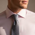 Muž v růžové košili s kravatou, detail na límec a uzel, profesionální módní fotografie.