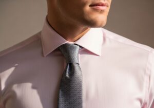 Muž v růžové košili s kravatou, detail na límec a uzel, profesionální módní fotografie.